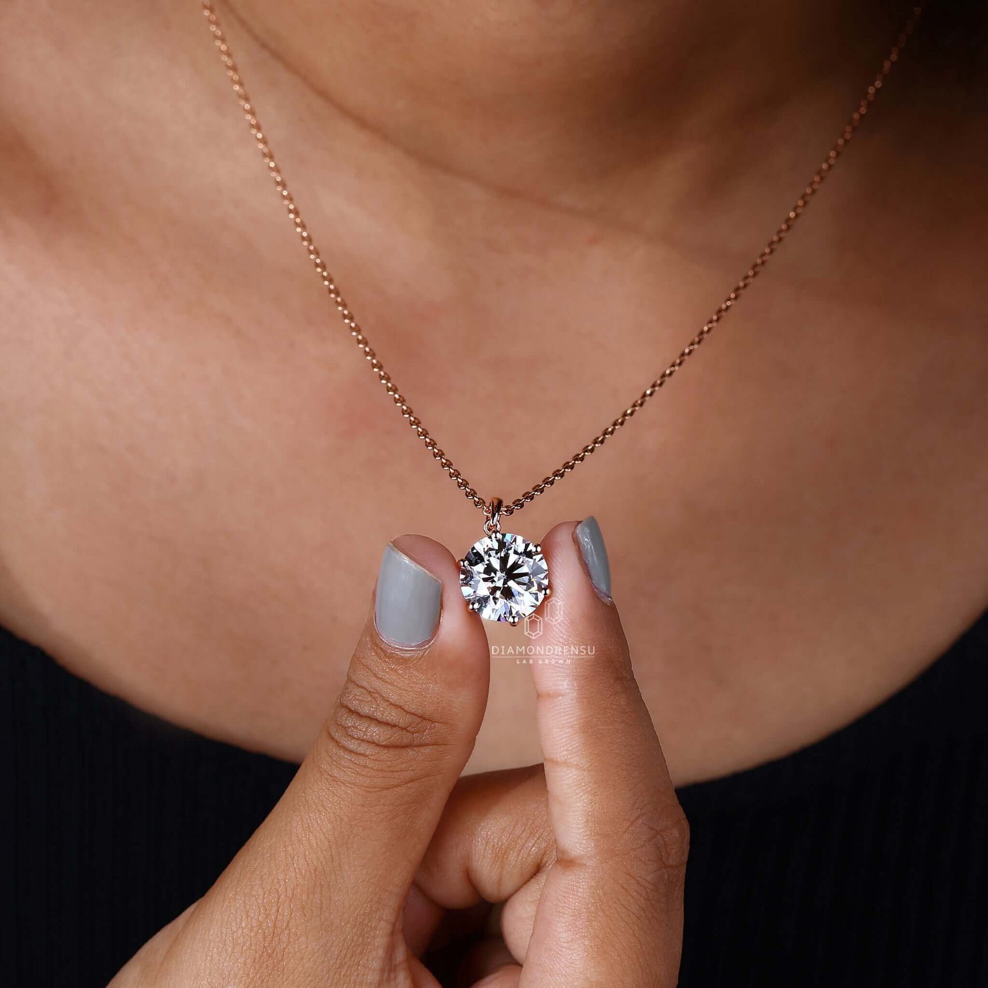 Model showcasing a round gold pendant with a solitaire diamond.