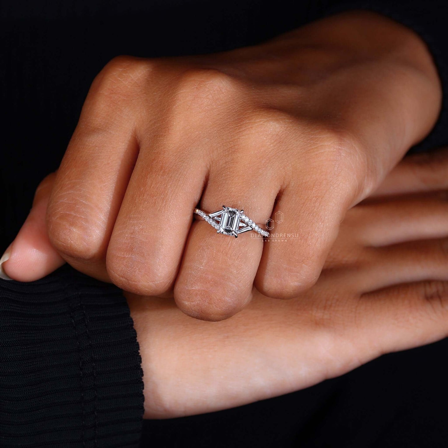 Close-up of an emerald cut diamond ring on hand, focusing on its luxurious and geometric cut.