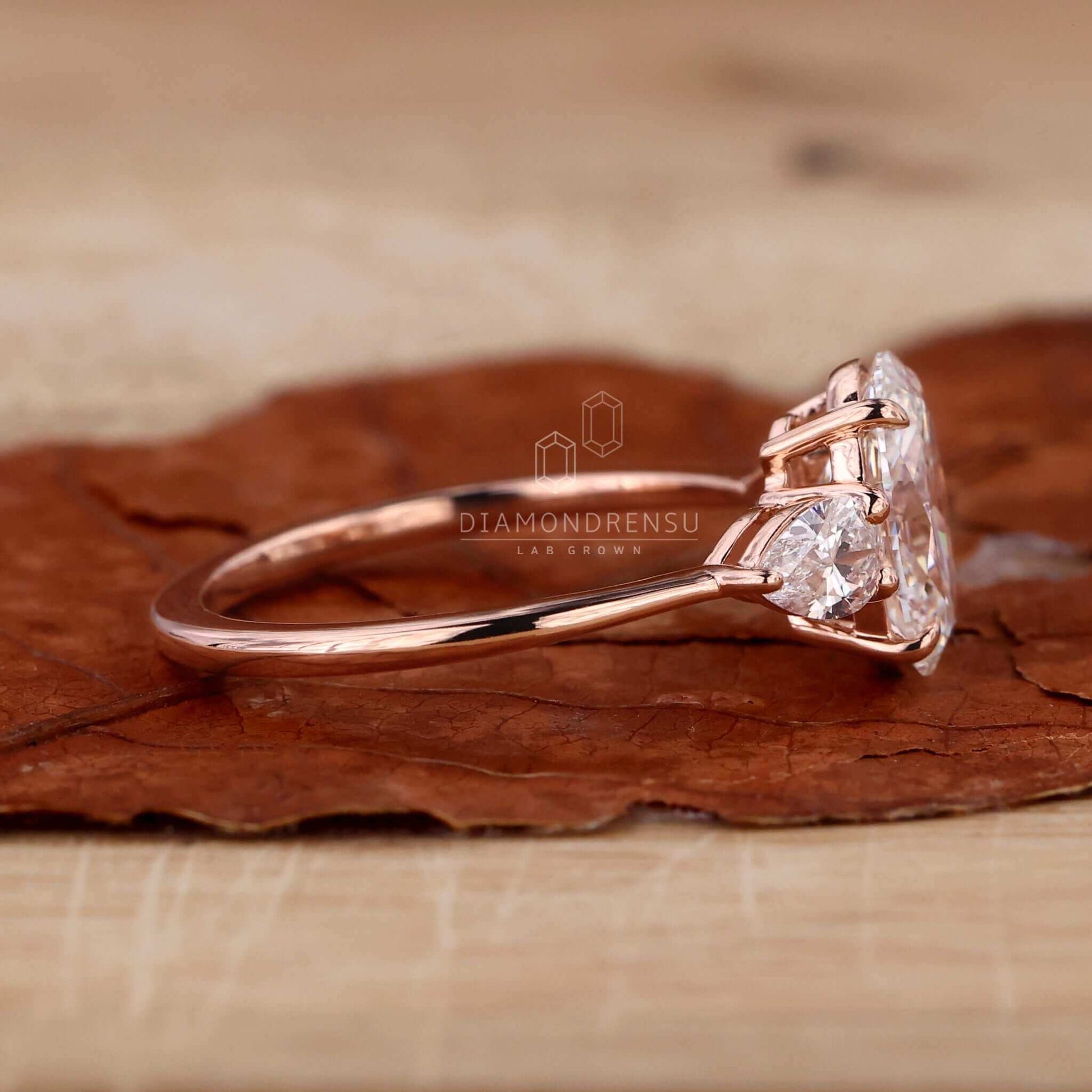 Oval engagement ring with pear side stones on a display stand