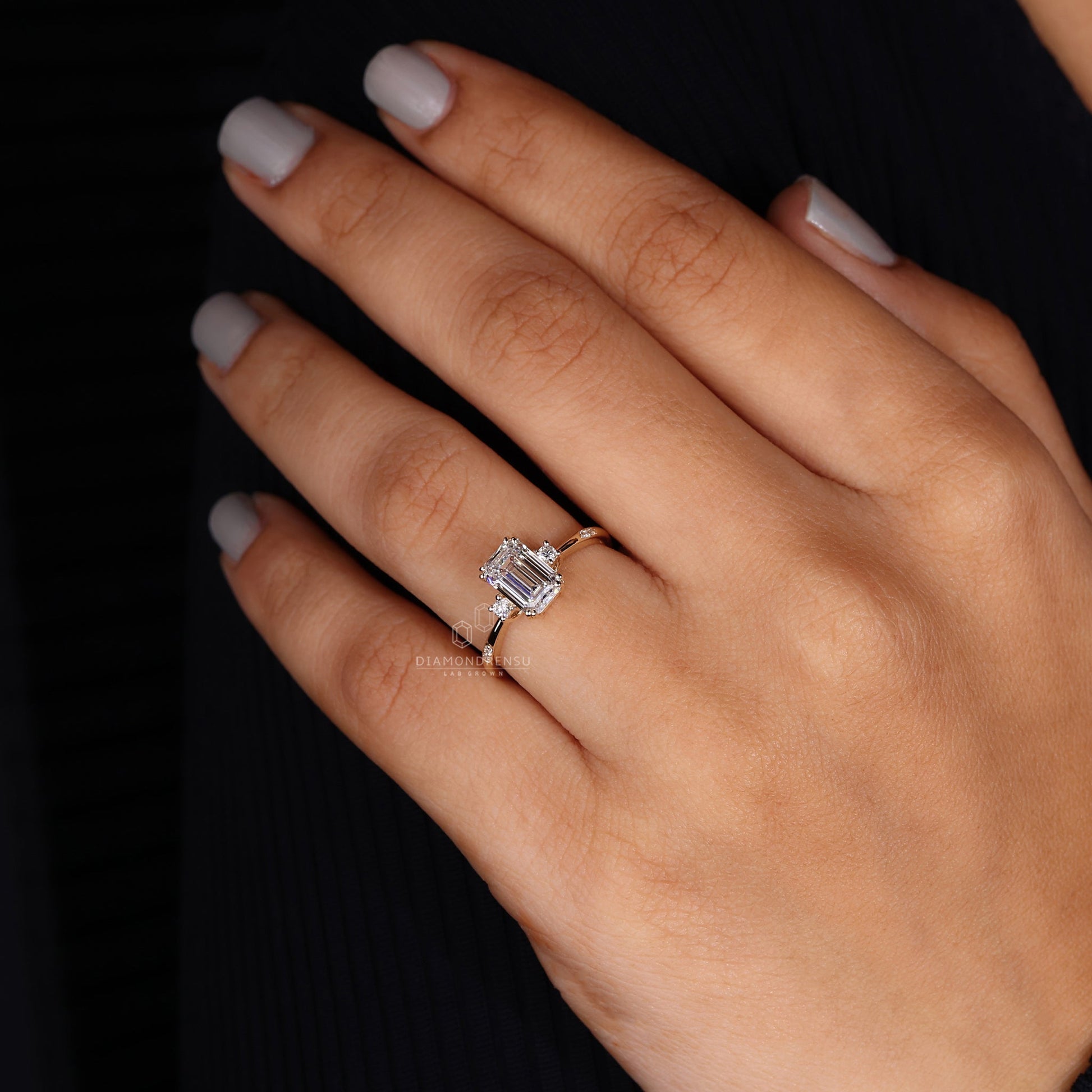 Profile view of a three stone emerald cut ring on a dark wooden surface