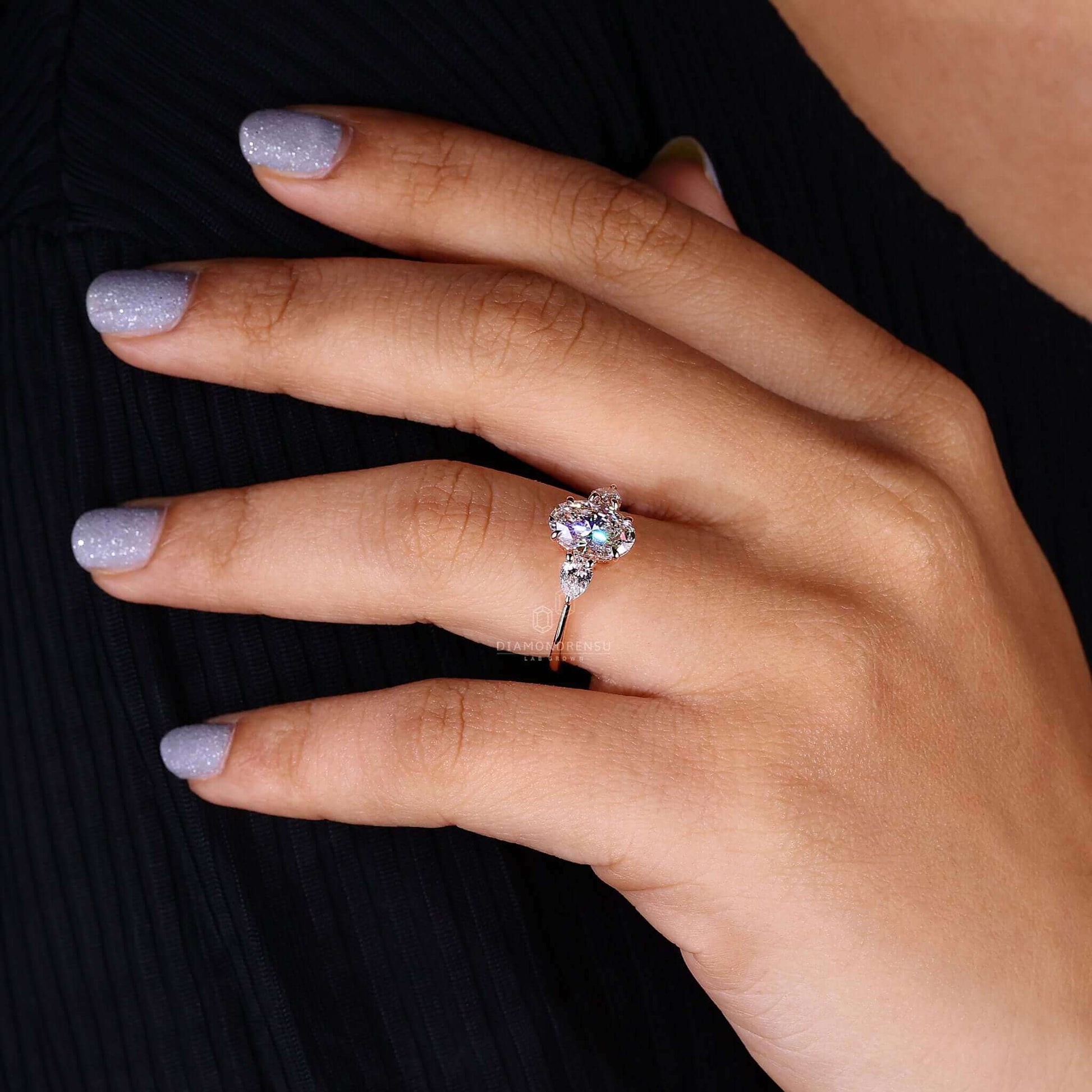 Model wearing an oval diamond ring with three stones and a rose gold band