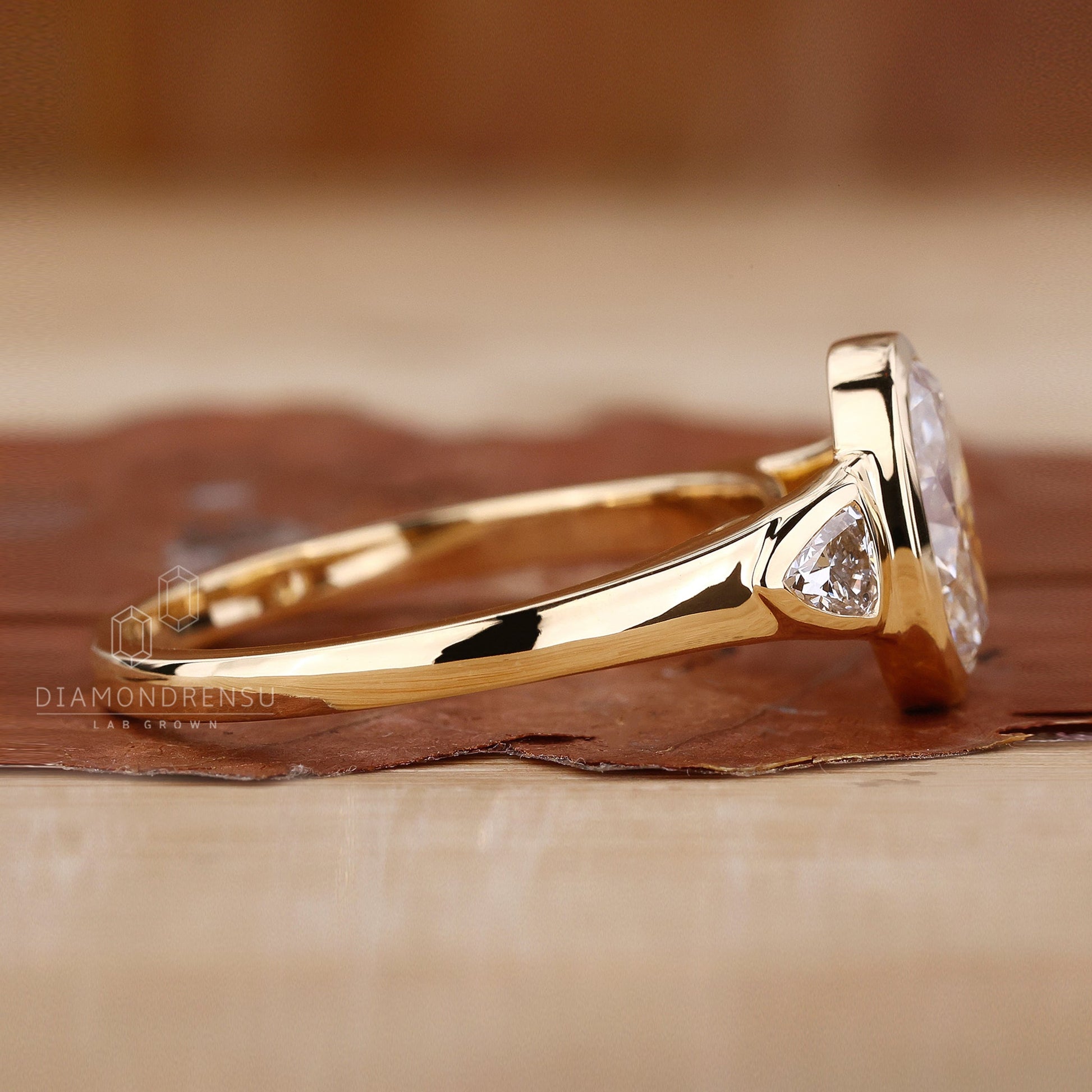 A profile view of an engagement ring featuring an oval center stone with two trillion side stones, highlighting its exquisite craftsmanship and intricate details.